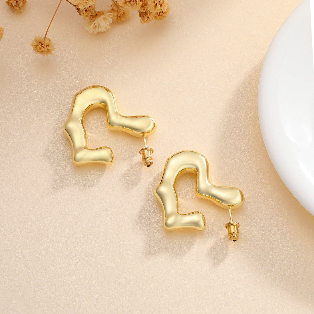 Golden-colored, flat-opening heart-shaped earrings